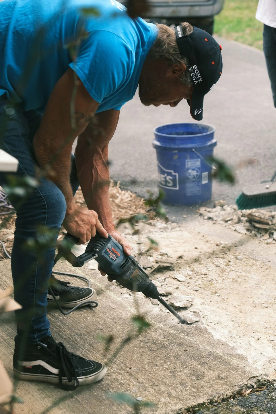 man in blue shirt and black shorts holding black and blue power tool
